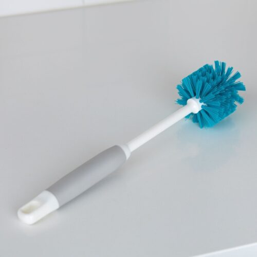 Simple ecommerce image of a blue scrub brush with white and gray handle shot on a kitchen table.