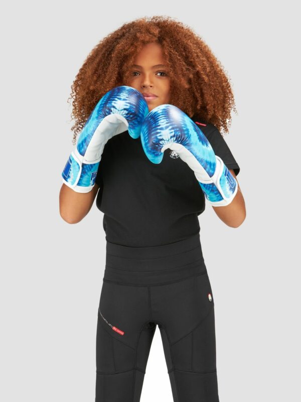 Action photography of female child model with curly hairs wearing sea green tie and dye boxing gloves.