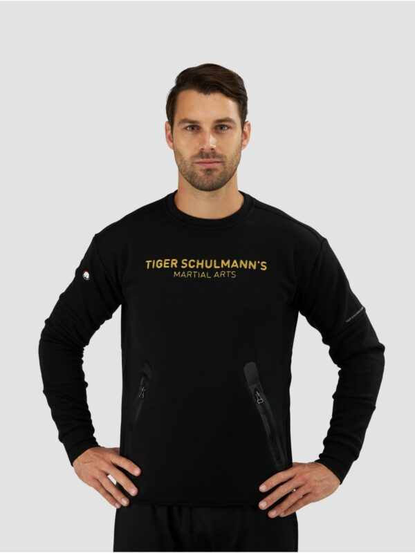 Clothing photography of a male model wearing sweat shirt in black with a “ Tiger Schulmann’s martial arts” text on the front.