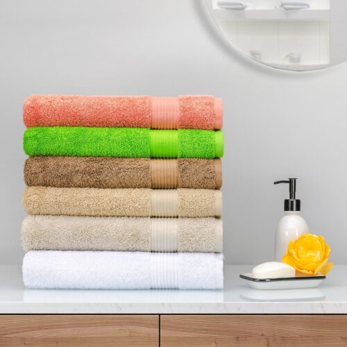Six multi color towels placed on top of each other with hand wash, soap and a flower placed on side to create a lifestyle setting.