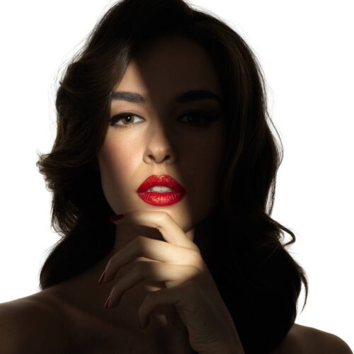 Creative beauty shot of a female white model wearing red lipstick using creative lighting by photographer Isa Aydin.