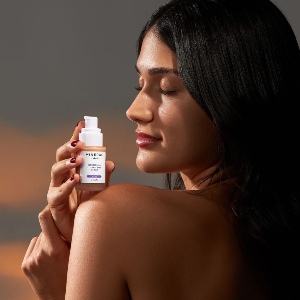 Profile of a serene woman with closed eyes, holding a bottle of moisturizing serum, emphasizing luxurious skincare on a warm-toned background.