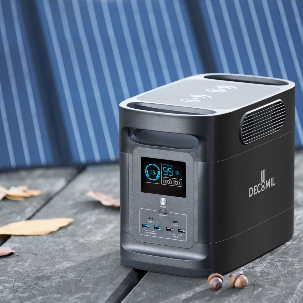 ChatGPT A compact solar power bank generator sits on a wooden surface with fallen leaves nearby, the portable charger's digital display lit and visible, next to a folded solar panel, illustrating the product's renewable energy feature for outdoor use.